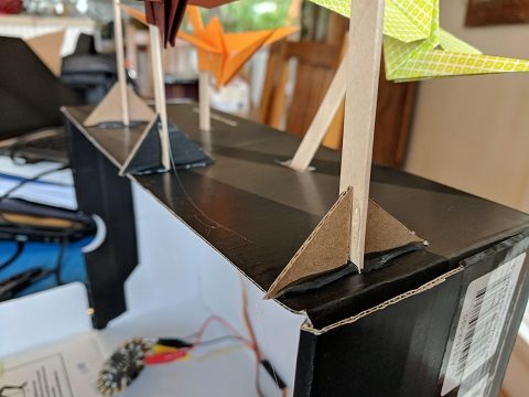 Popsicle sticks mounted to the top of the box with the help of cardboard gusset brace