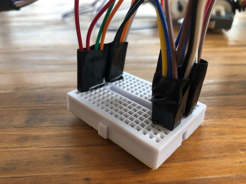 Wires with tape around them on a mini breadboard